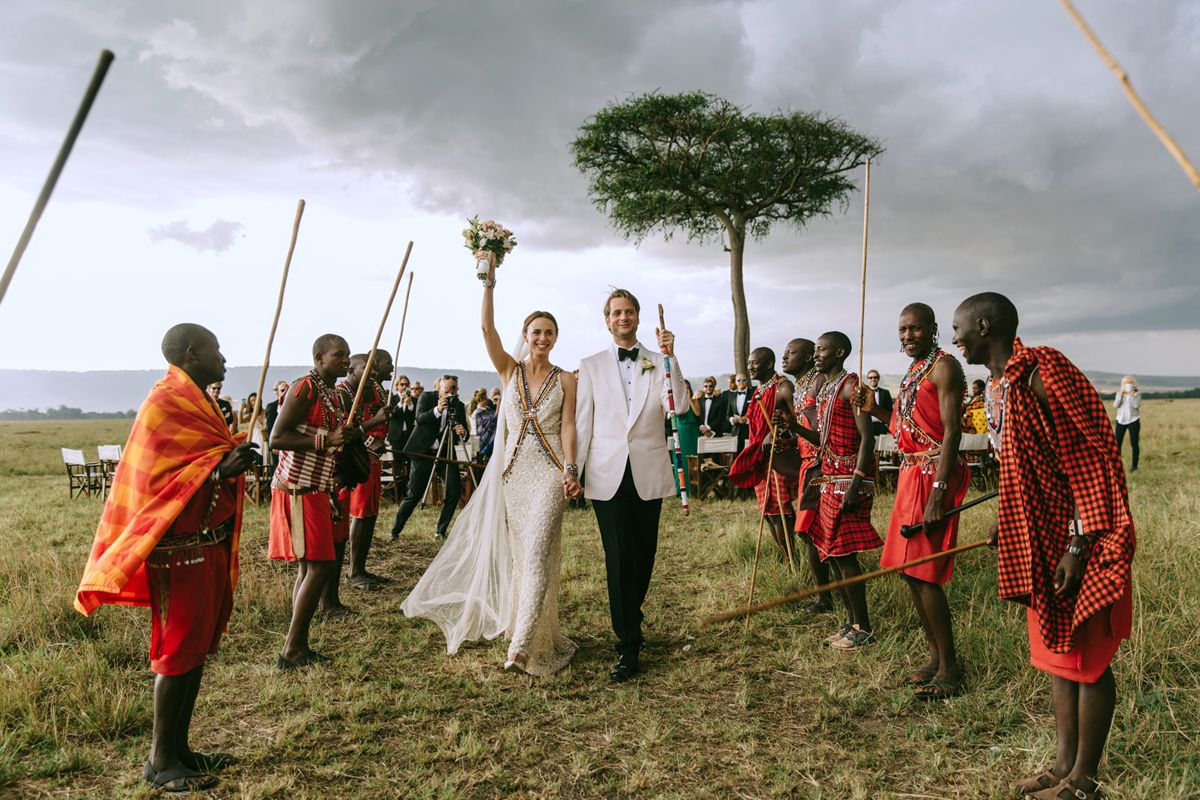 Newlyweds walking between Maasai attendants
